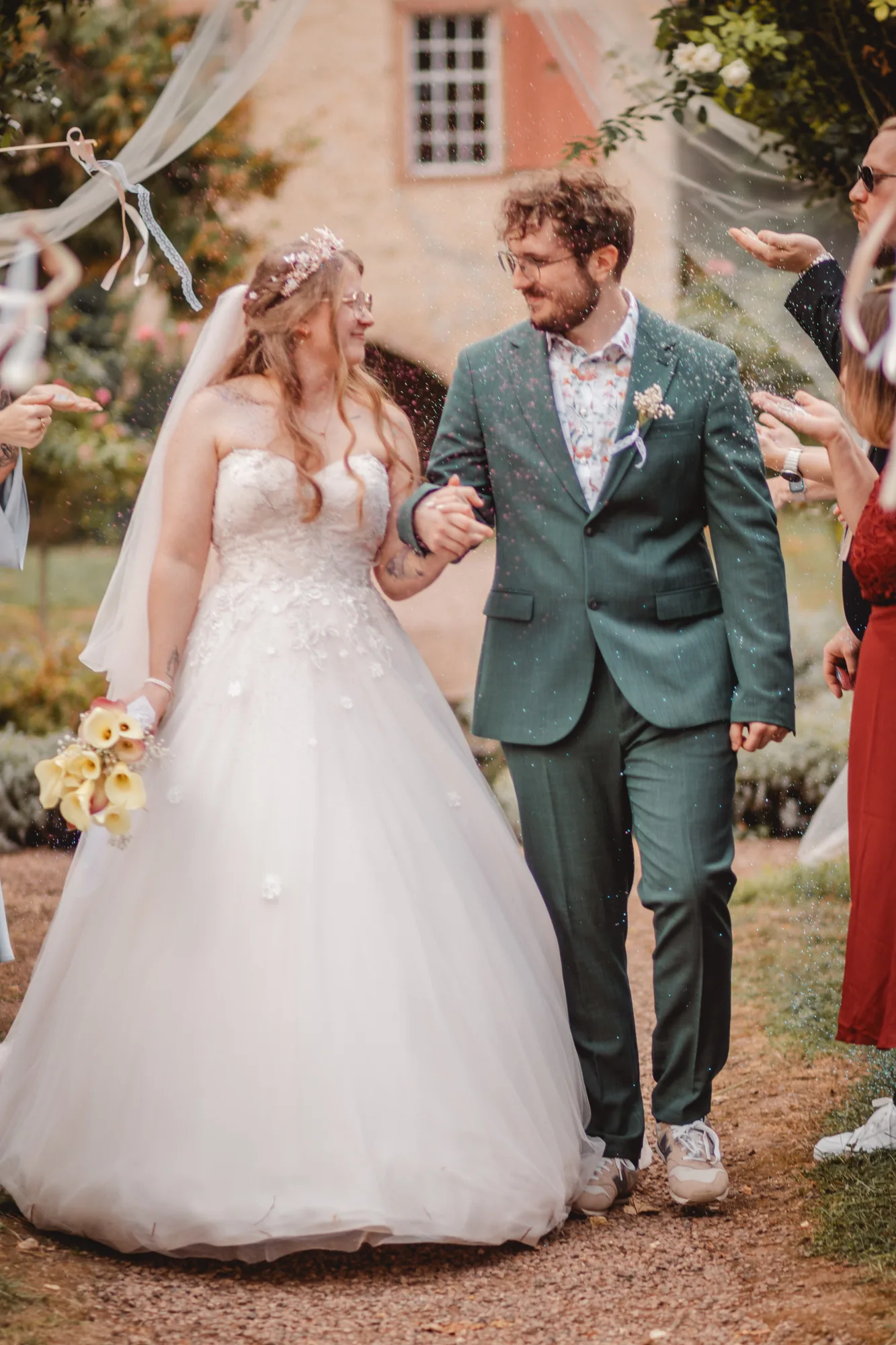 Das Hochzeitspaar läuft nach der Disney-Trauung Hand in Hand durch einen Regen aus buntem Glitzer.